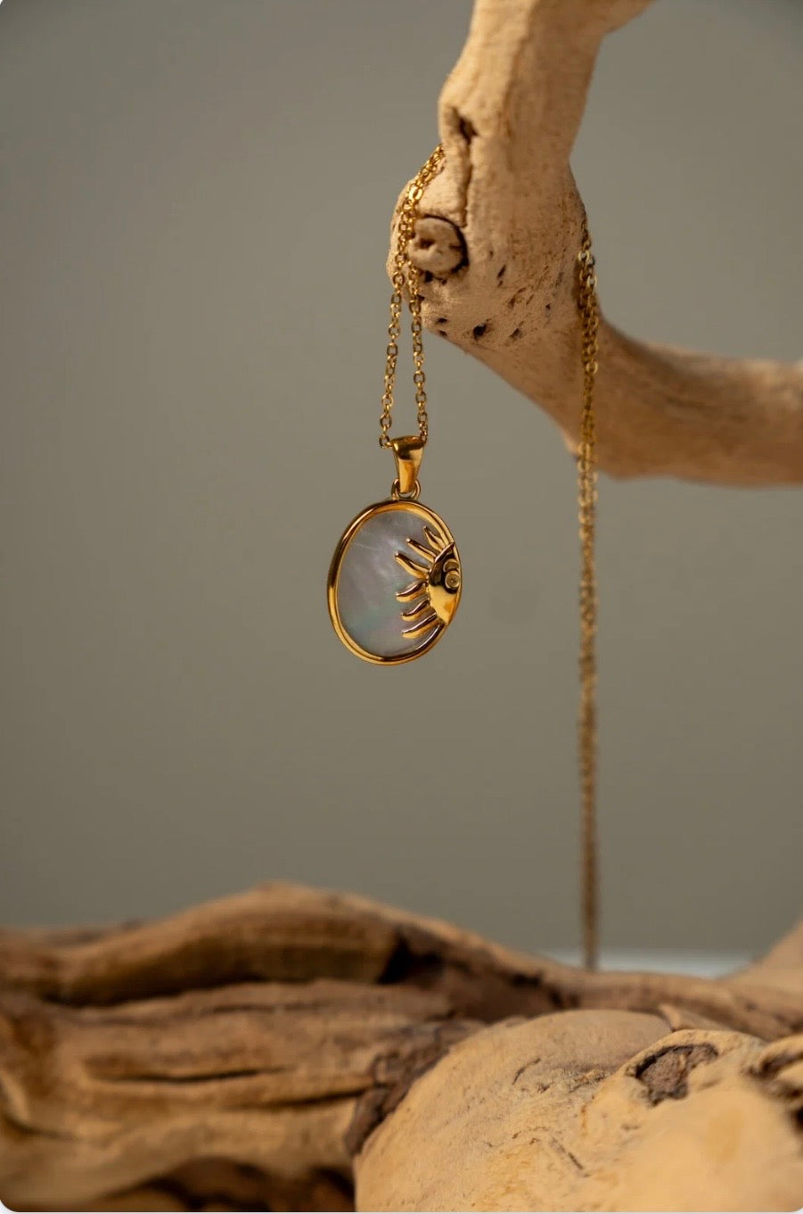 Gold necklace with a pendant on a natural wood background